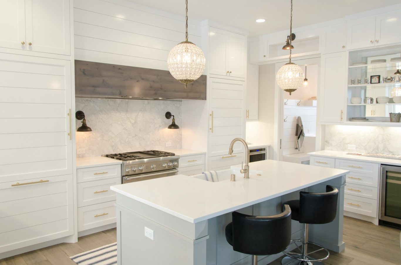 Modern Kitchen Remodel in Naples FL with white cabinets, wood floors, gold accents and white counters.