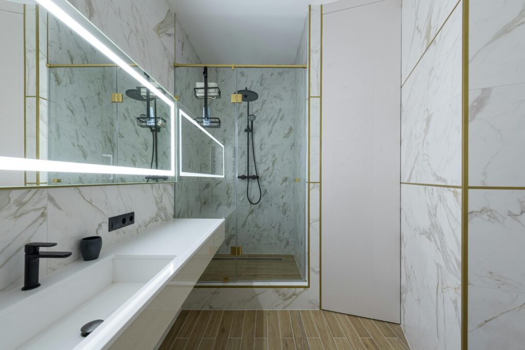 Modern bathroom remodel featuring a marble design, walk-in shower, and illuminated mirrors.
