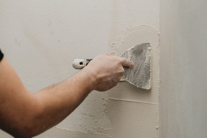 A handyman repairing drywall in a home in Golden Gate, FL.