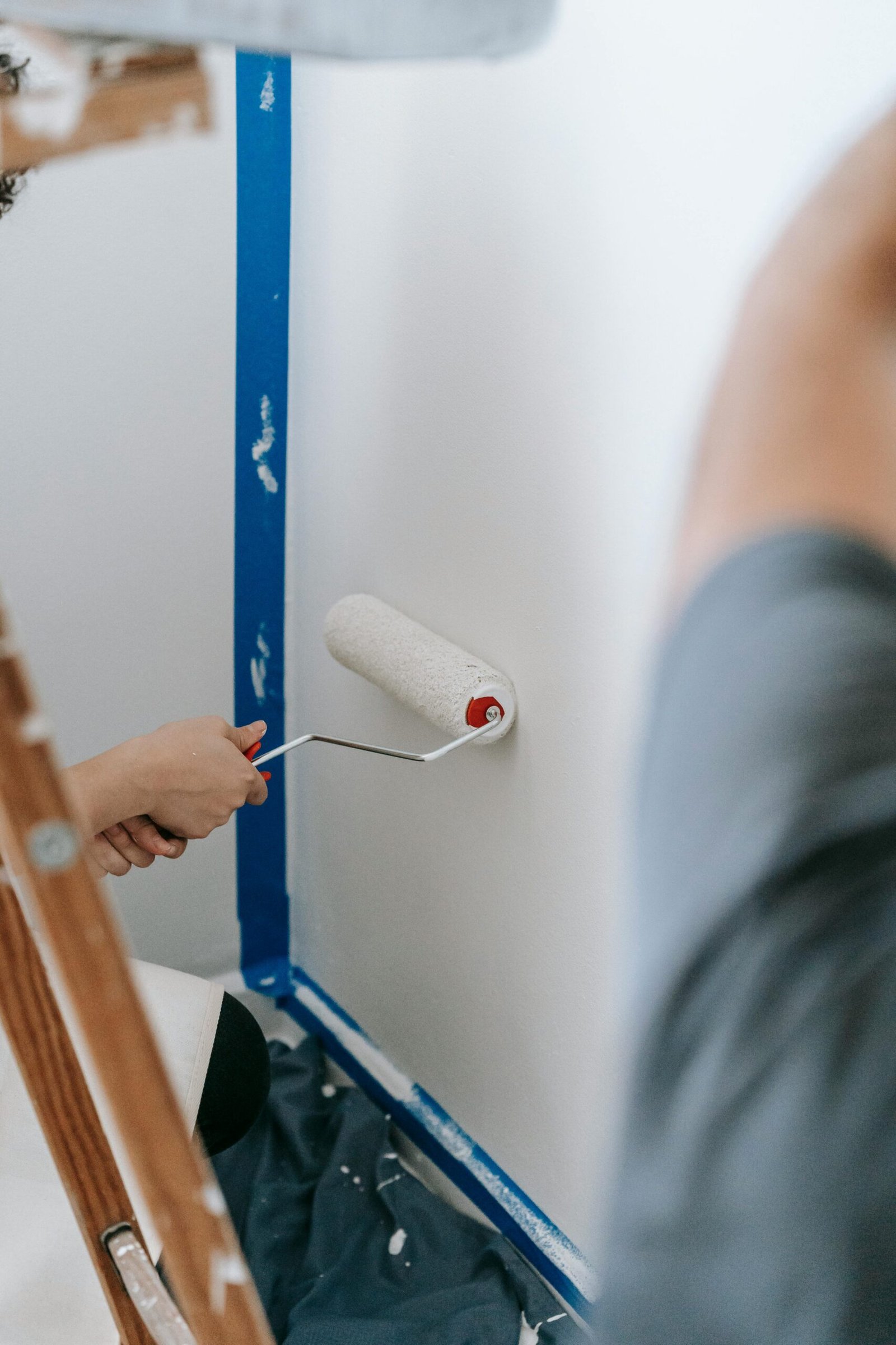 Handyman painting a wall white with a roller in North Naples.
