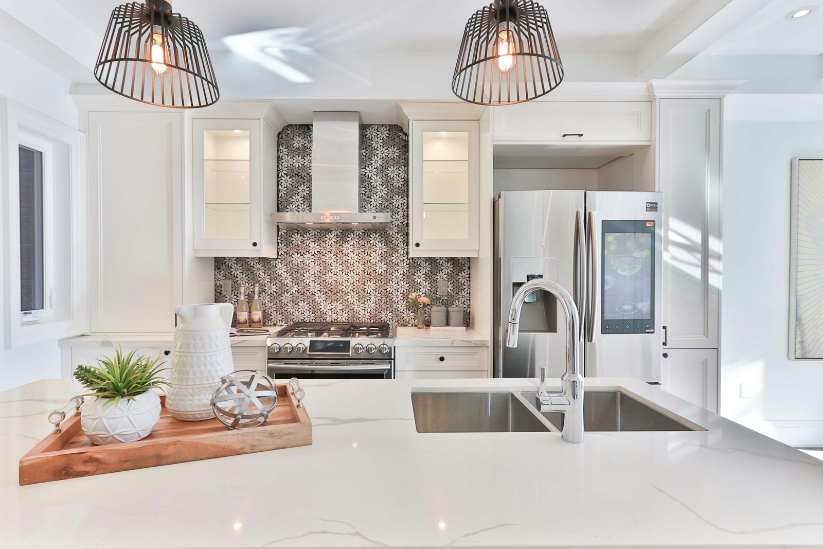 Modern kitchen remodel with marble counter tops, white cabinets, and flower shaped white and grey backsplash in Estero.