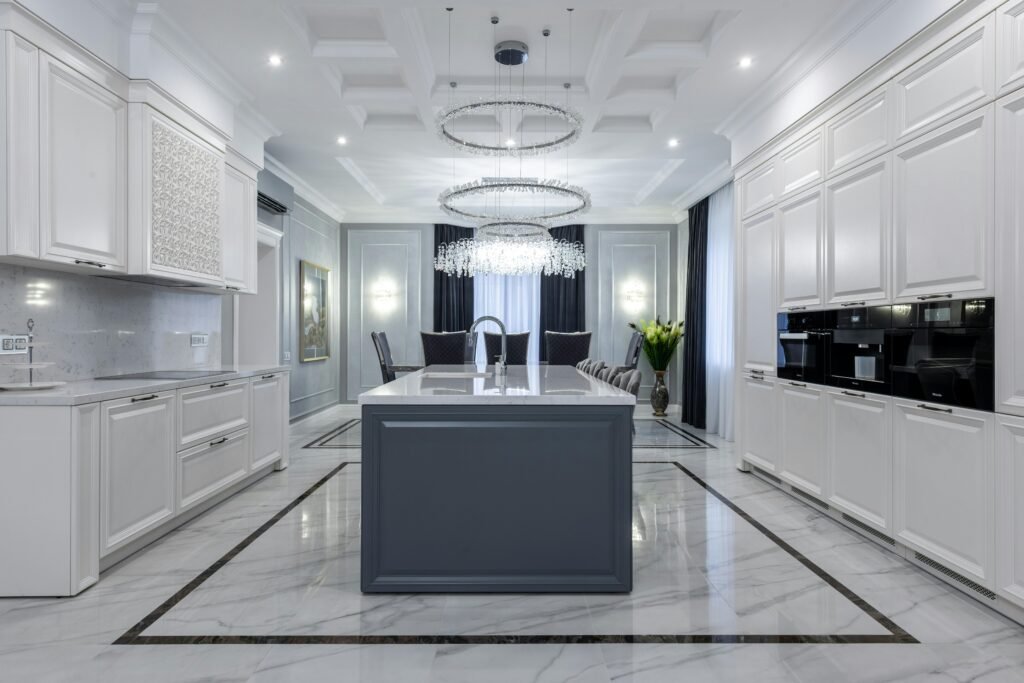 Modern kitchen remodel with a central island, white cabinetry, and elegant lighting.