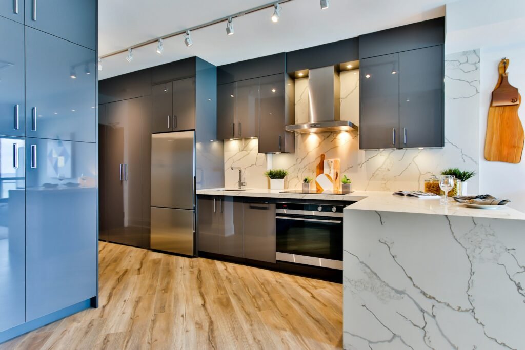 Modern Kitchen with glossy, grey cabinets, marble counters, and wooden floors in Naples.