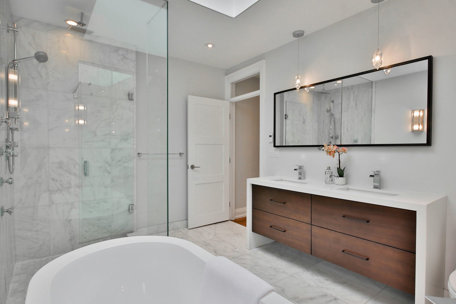 A modern bathroom with brown cabinets, white countertops, and a glass shower in Marco Island.