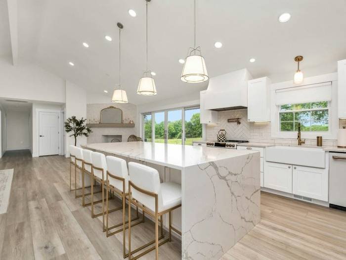 Modern kitchen with white cabinets, marble countertops and wood floors in Naples.