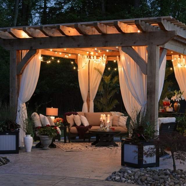A cozy outdoor seating area with a pergola, new tile, and curtains in Old Naples.