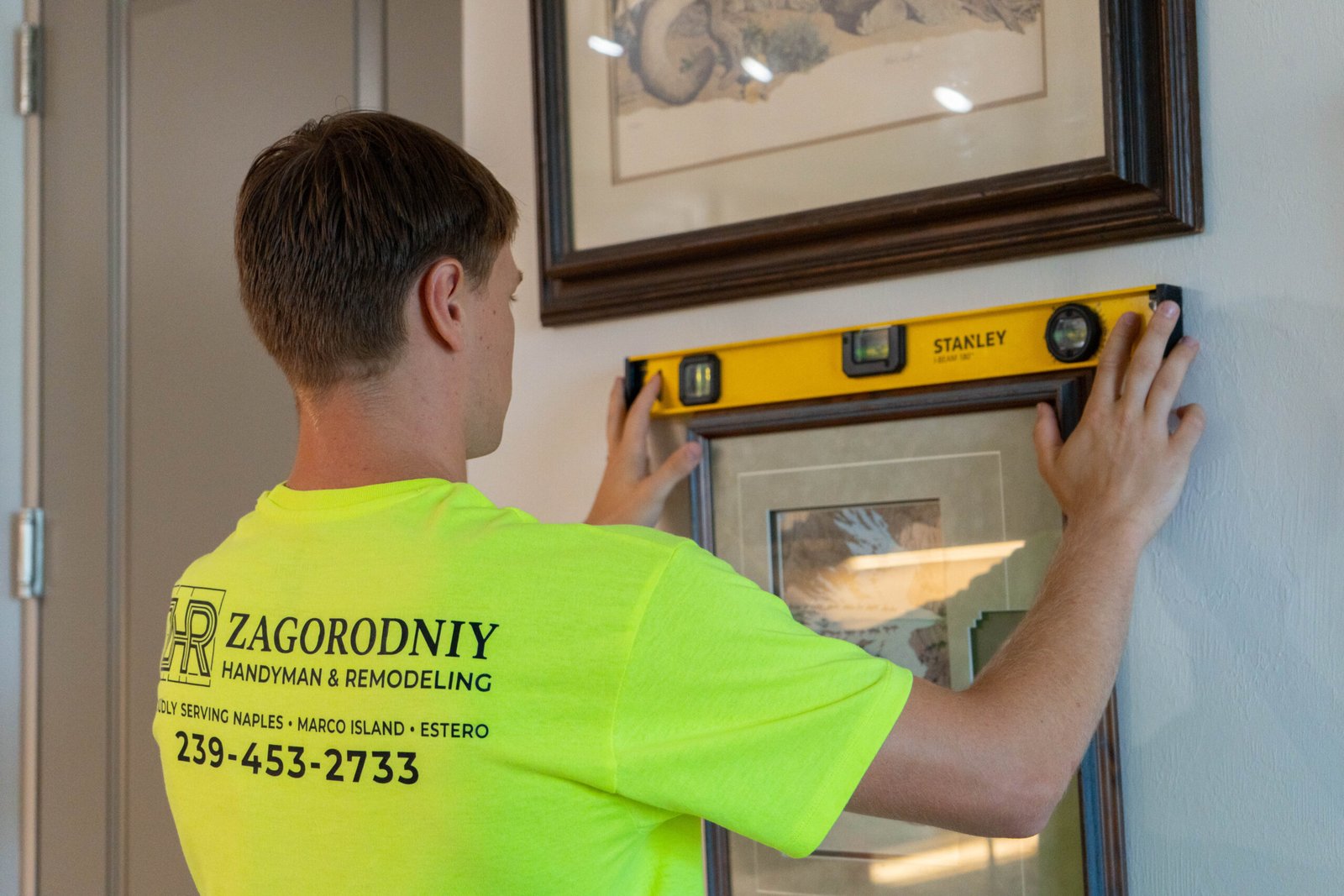 Handyman leveling a piece of art in a home in Lely Resort.