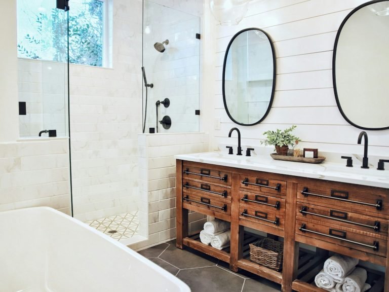 Modern bathroom with a wooden vanity, two mirrors, and a glass shower in Bonita Springs, FL.