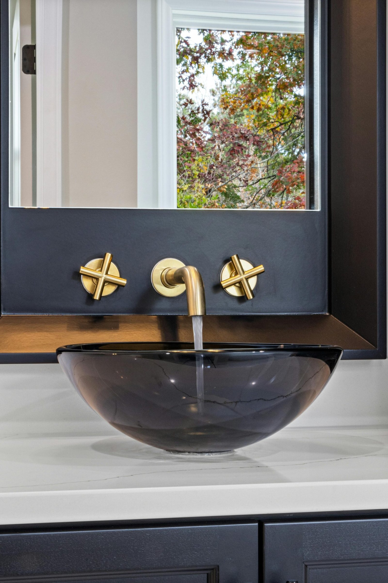 Modern bathroom vanity. Gold faucet, black sink bowl, and white vanity top in Marco Island.