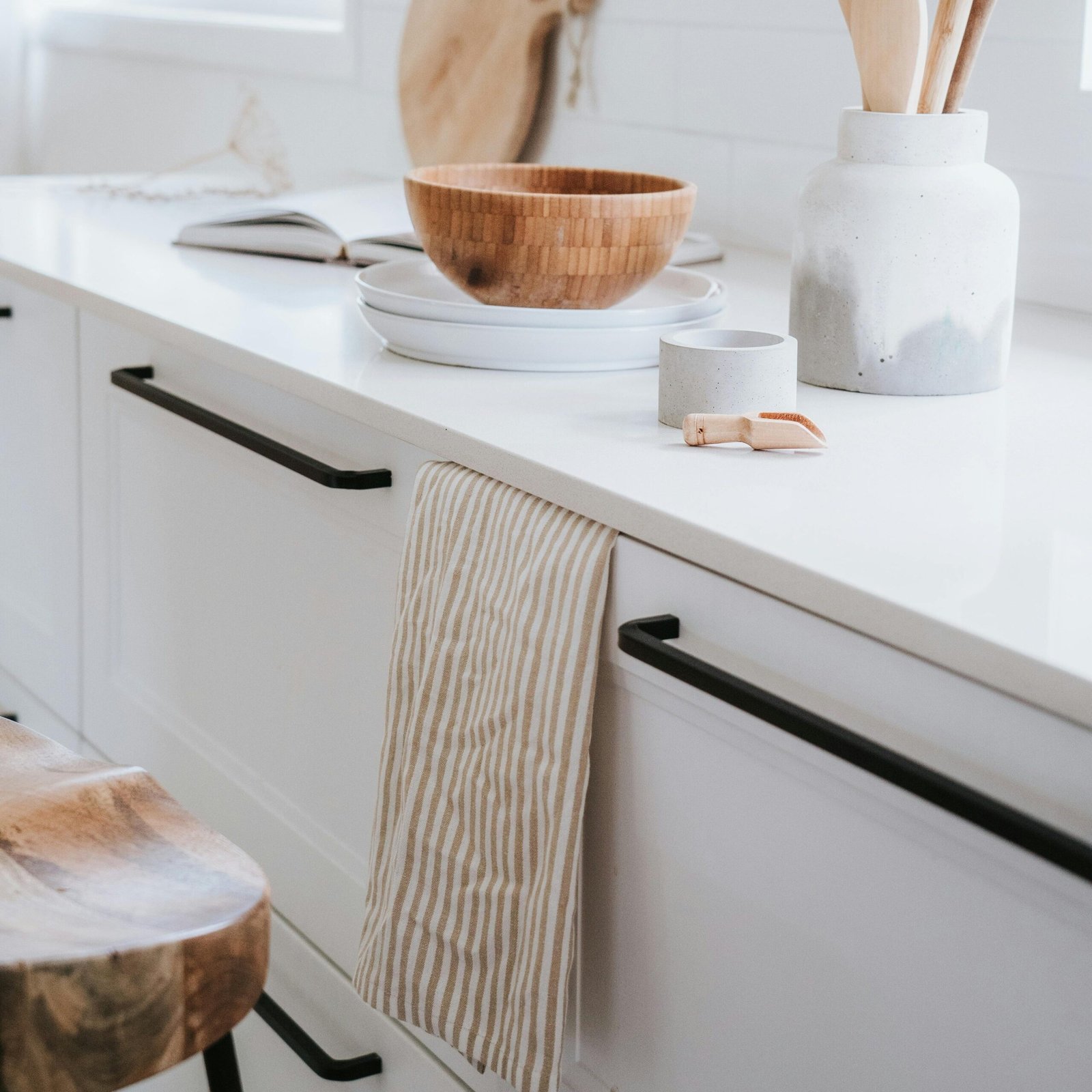 A minimalist kitchen counter with wooden utensils, bowls, and matte black hardware.