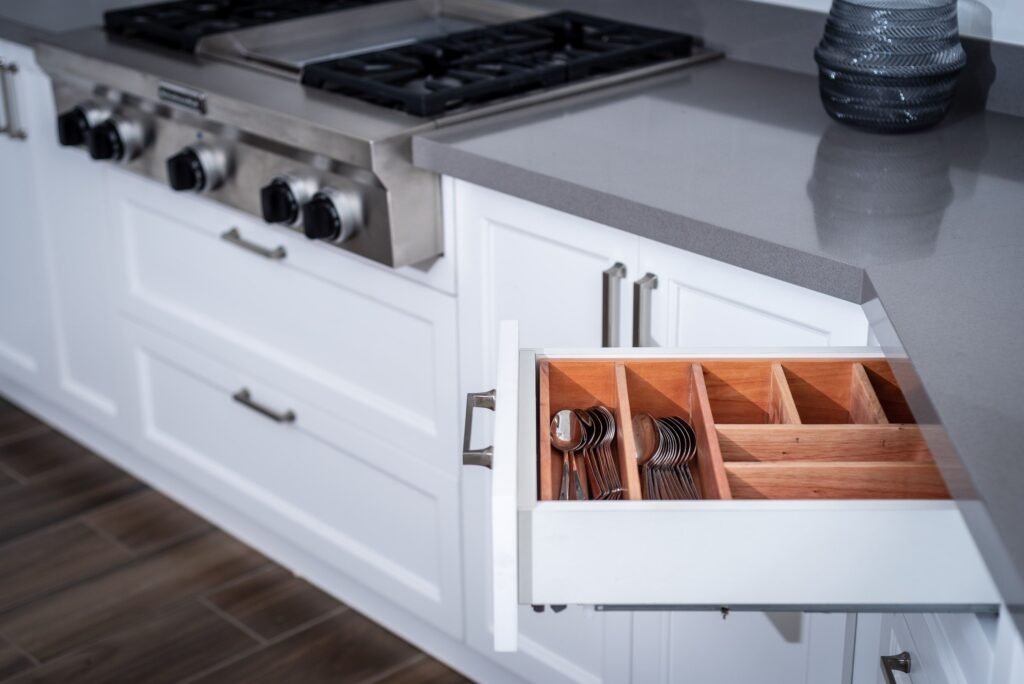 White kitchen drawer partially open, revealing wooden dividers for utensils and tools in North Naples.