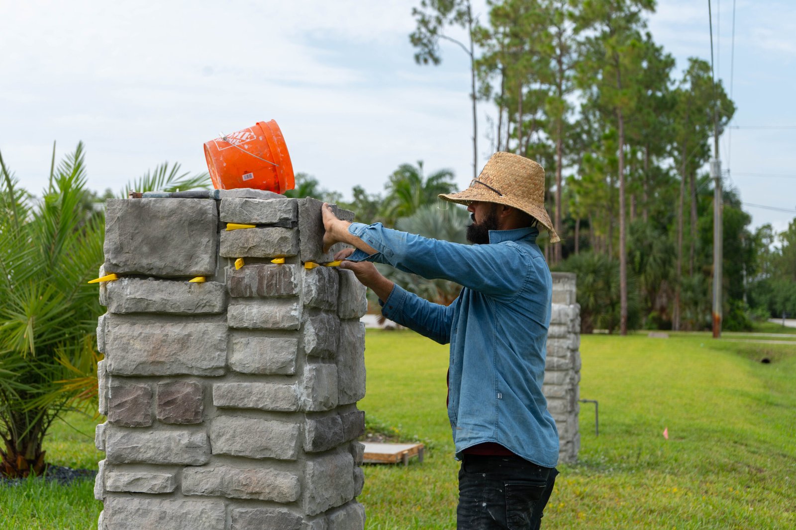A worker applying stone veneer to a custom column in Bonita Springs.