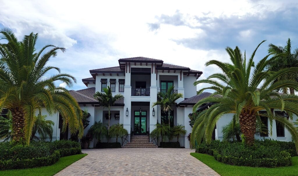 Modern, white home with palm trees in the font and a paver driveway in Naples.