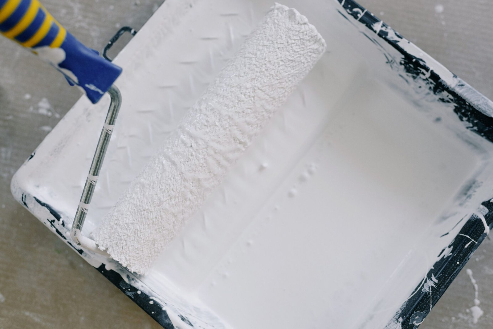 A paint trey with white paint and a roller brush in Naples.