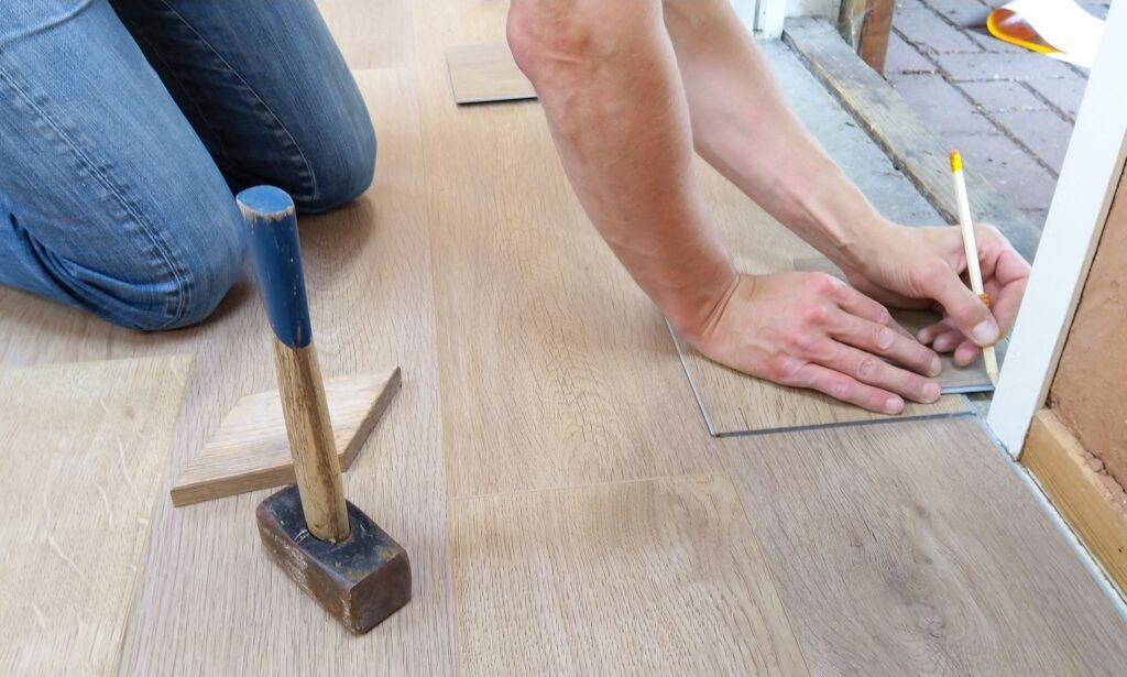 A handyman installing LVP flooring near a white door frame in Bonita Springs.