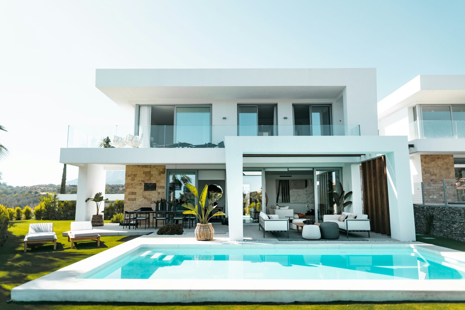 A modern, white house with a pool and plants around the house in Naples.