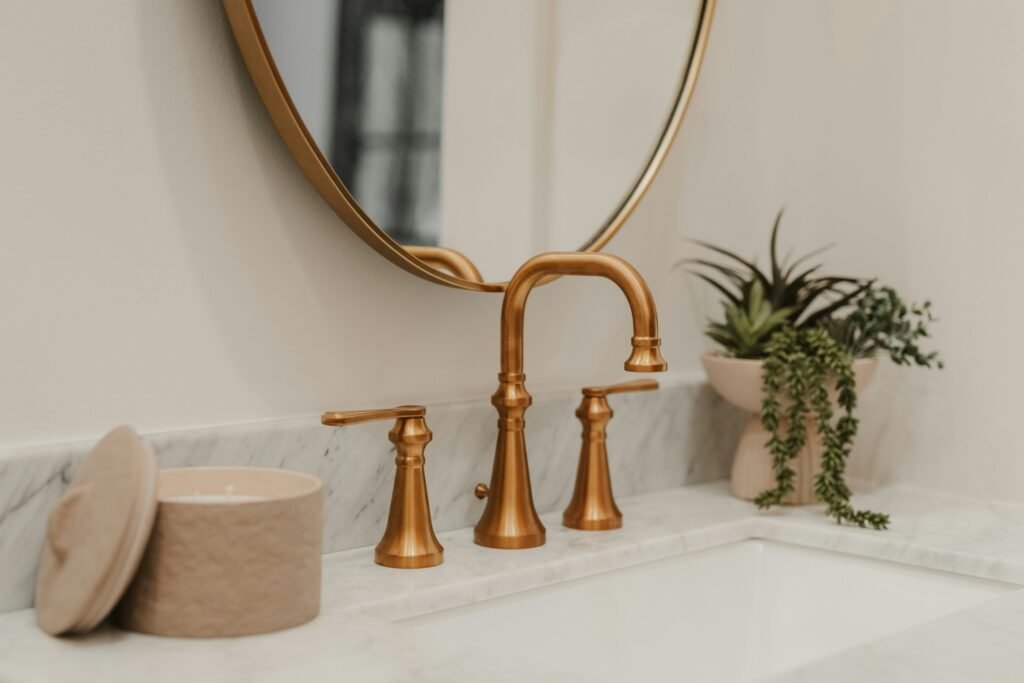 New bathroom faucet installed in North Naples. Gold faucet, marble counter top and a gold rimmed mirror.