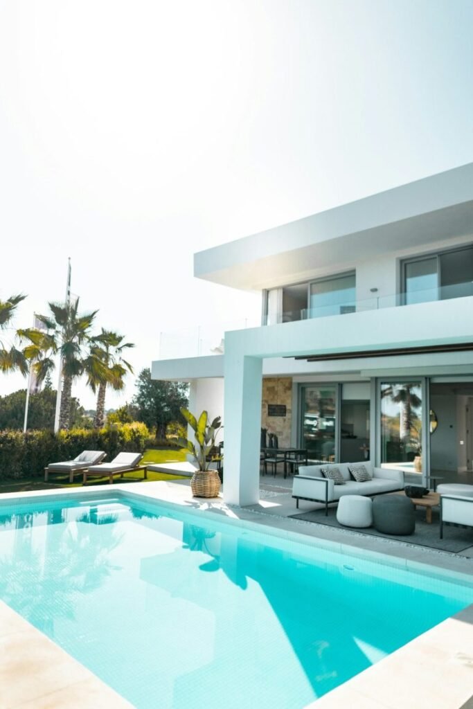 Modern white house in Naples, FL with a pool and some patio furniture.
