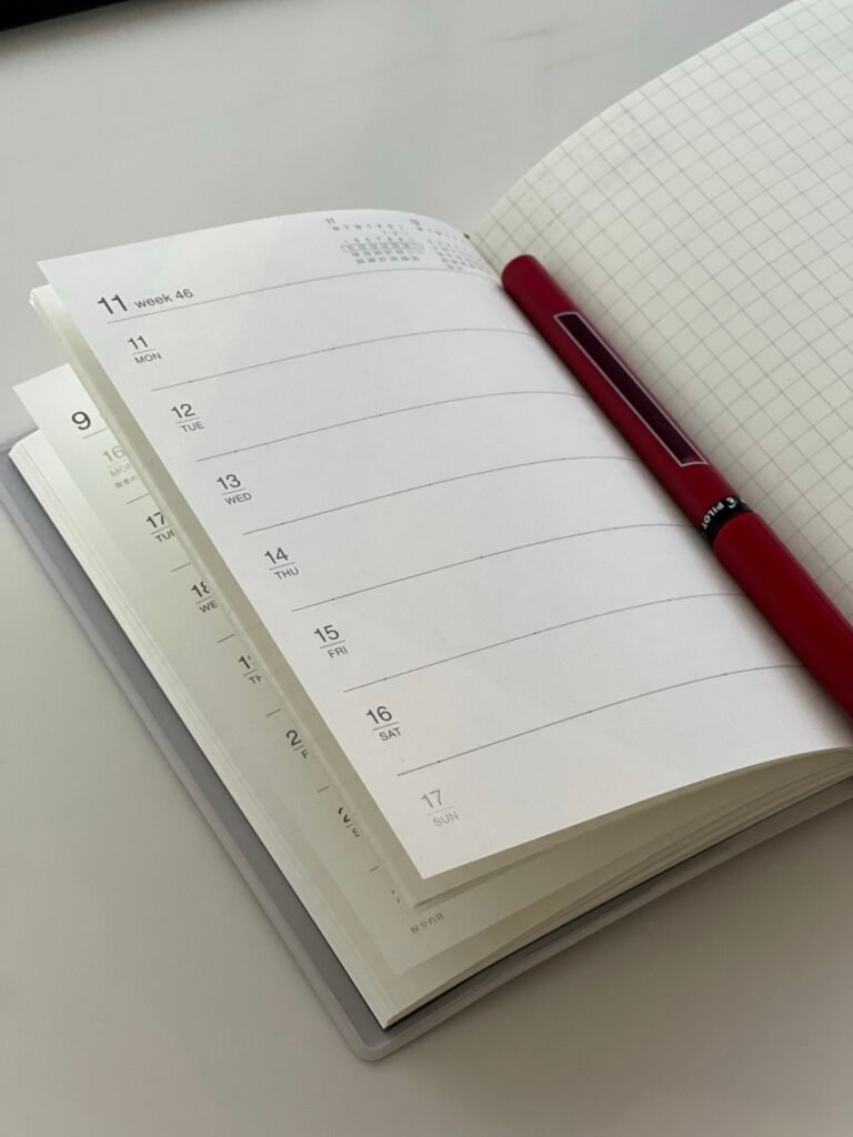 A blank planner with a red pen in the crease.