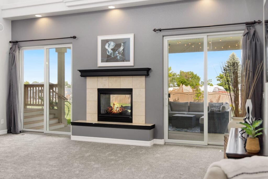 Cozy living room with a fireplace, large windows, and modern decor.