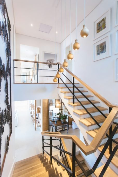 Modern staircase with wooden steps, black railing, and pendant lights. Bright and open space in Marco Island, FL.