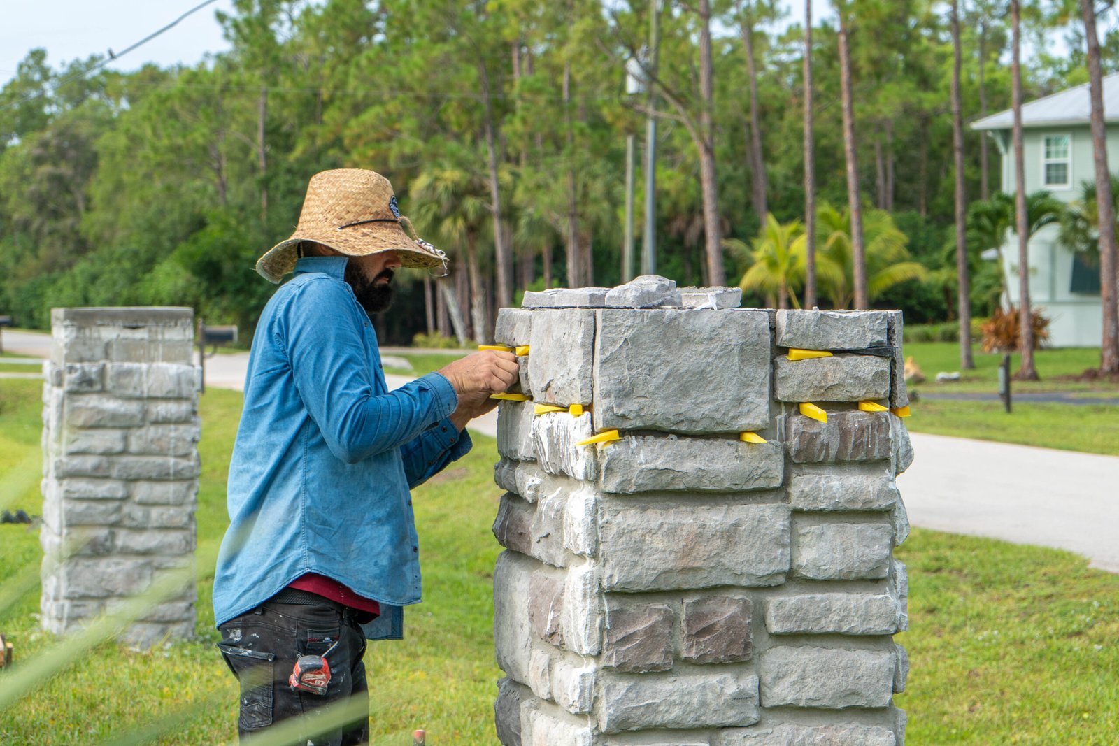 A handyman installing new stone veneer on a column in Bonita Springs.