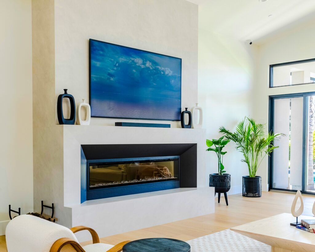 Modern living room with a fireplace, TV on the wall, and green plants in decorative pots in Marco Island.