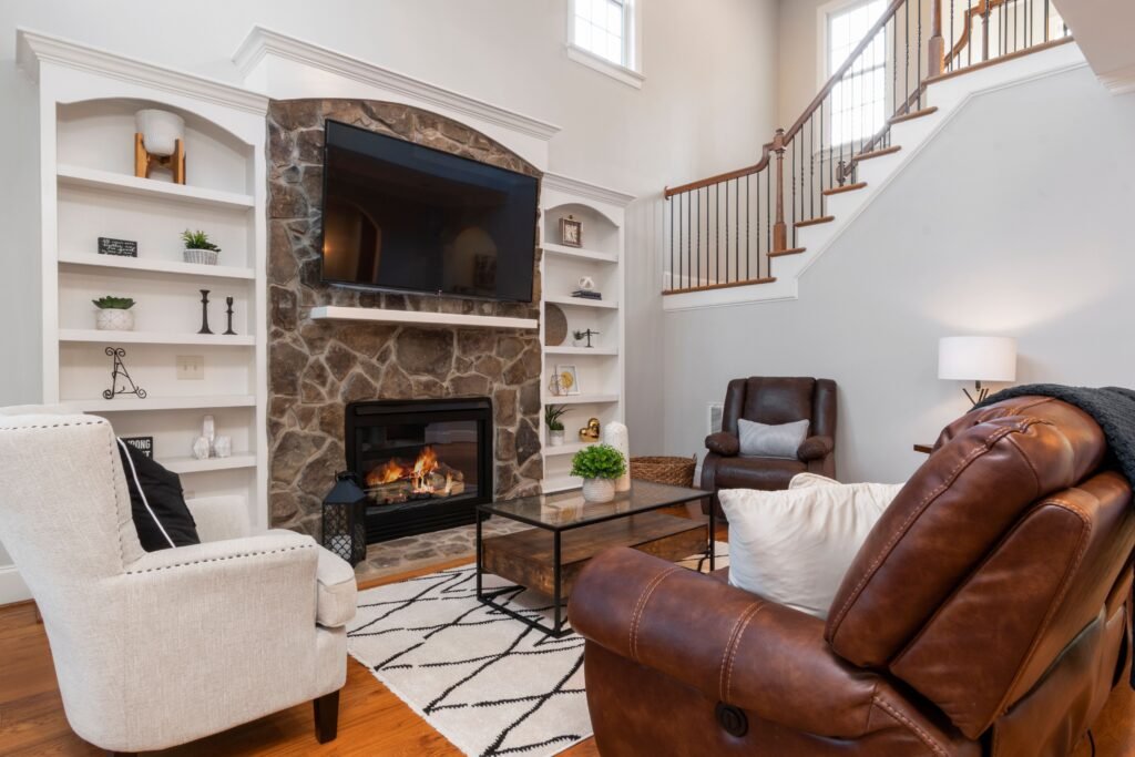 Cozy living room with a stone fireplace, a mounted TV, armchairs, and a glass coffee table in Old Naples.
