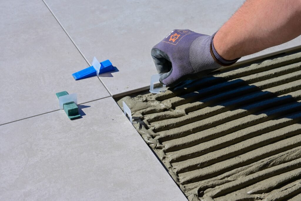 A handyman installing large, grey tile flooring in a Marco Island home.