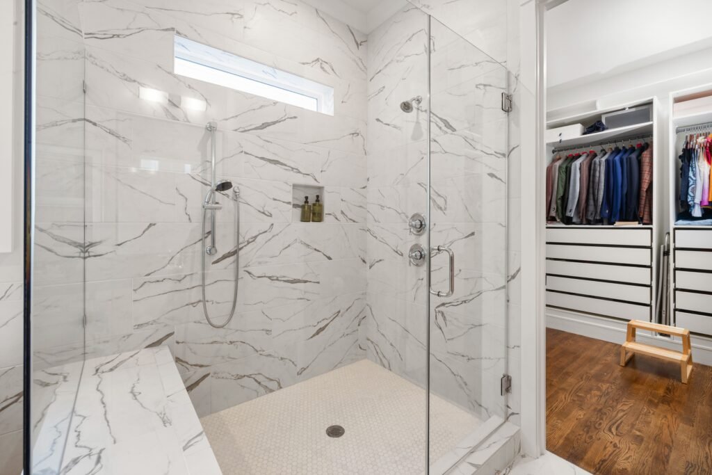 Modern shower with marble walls, glass enclosure, and a rainfall showerhead in North Naples.