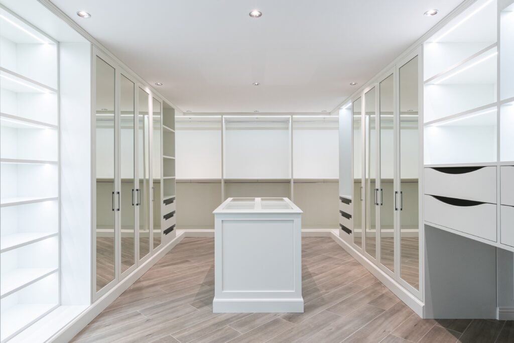 Modern, minimalistic closet with white shelves and cabinets, featuring a central island in Old Naples.