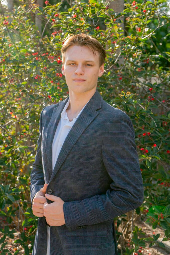 ZHR owner, a young man in a blue suit jacket with a plant in the background in Naples.
