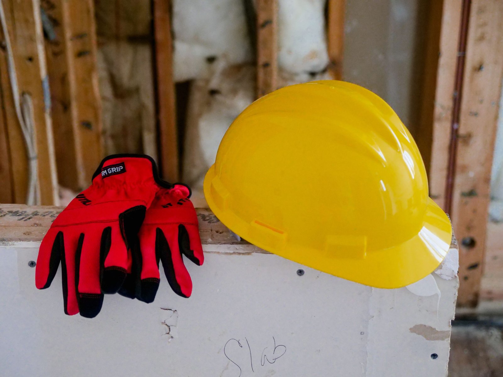 A yellow hard hat and red gloves on some pieces of drywall on a commercial job site in Naples.